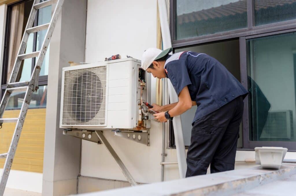 HVAC technician servicing an outdoor air conditioner unit