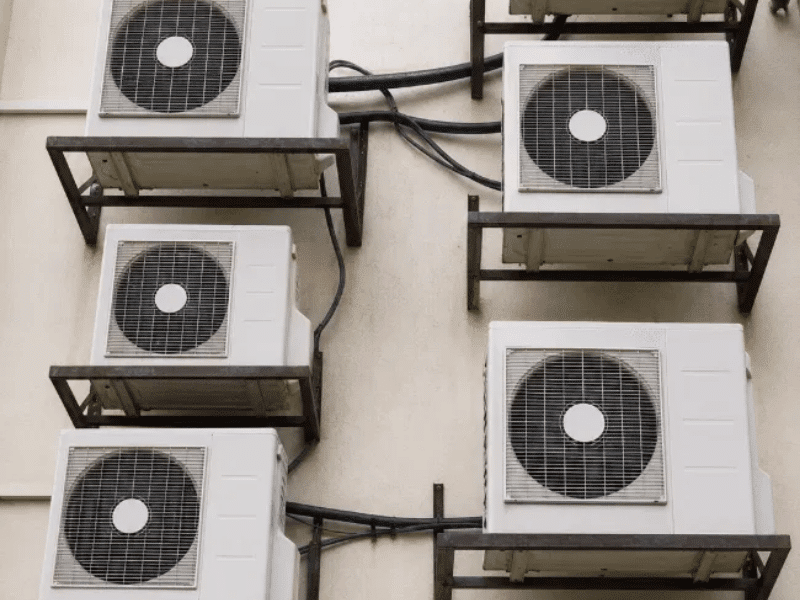 Multiple split air conditioner outdoor units mounted on a building with refrigerant line routing