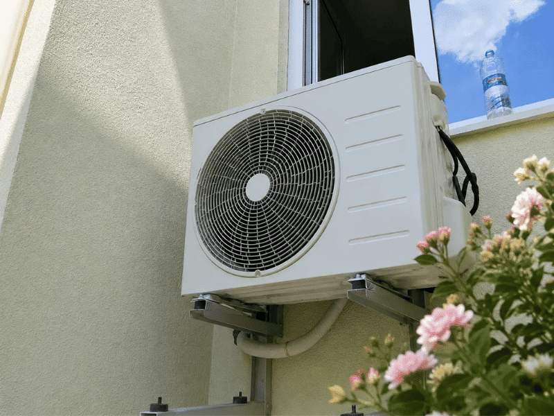 Wall-mounted split air conditioner outdoor unit installed beside a residential balcony