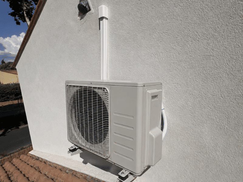 Split air conditioner outdoor unit mounted on a wall bracket with protected service conduit