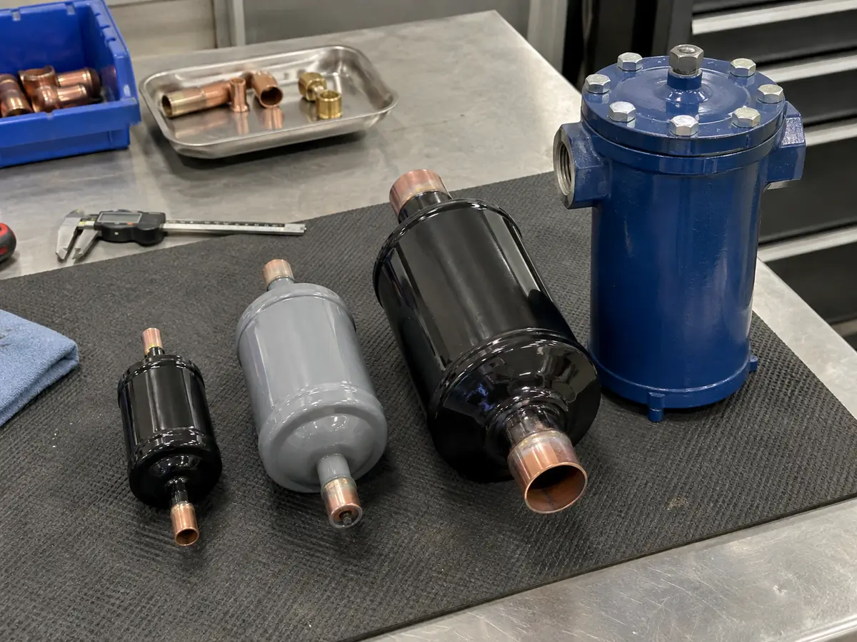 Different HVAC filter drier component formats arranged on a workshop bench.