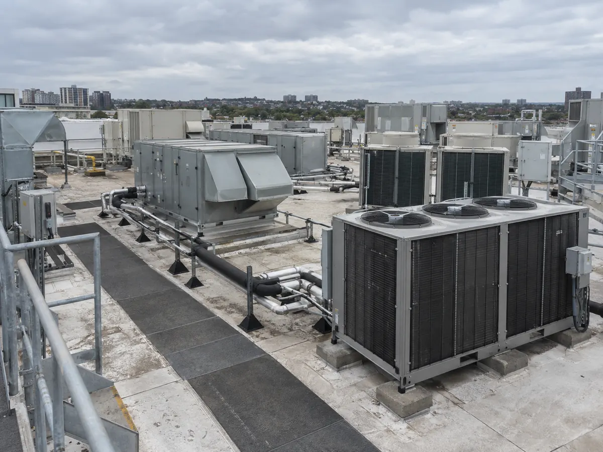 Large commercial rooftop with several generic HVAC outdoor-unit types serving one modern building.