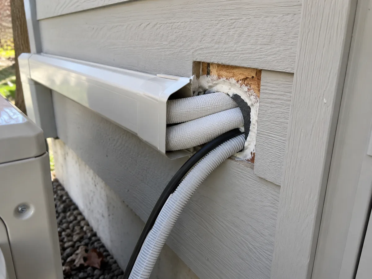 Unfinished wall penetration with insulated refrigerant piping and a drain line