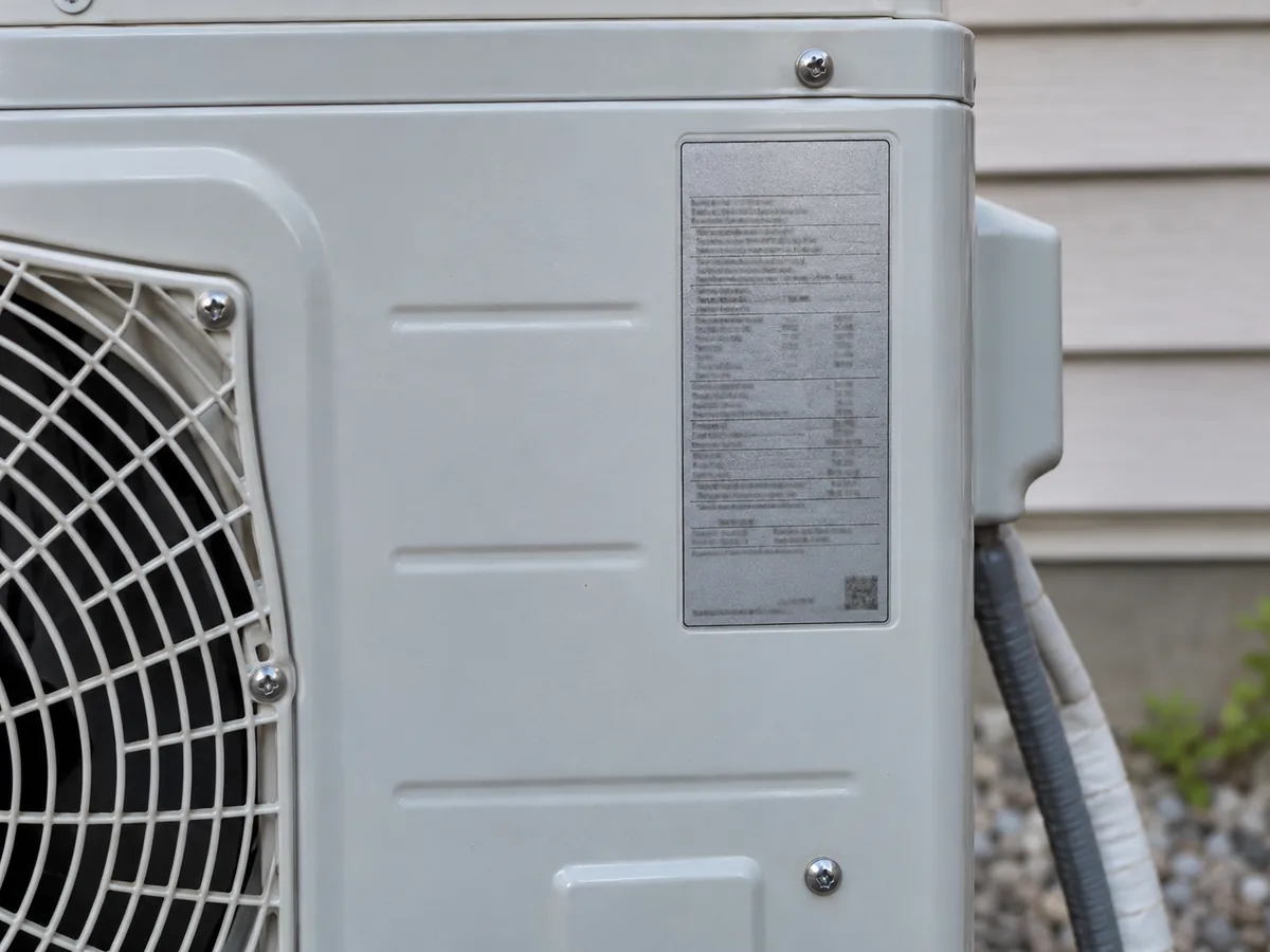 Identification label on the side of an outdoor heat pump unit with intentionally unreadable specifications