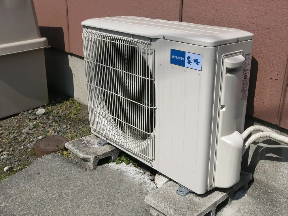 Outdoor air conditioning condenser supported on masonry blocks outside a building